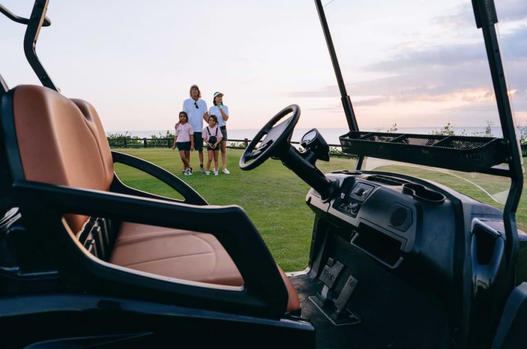 Golf cart with family in background.