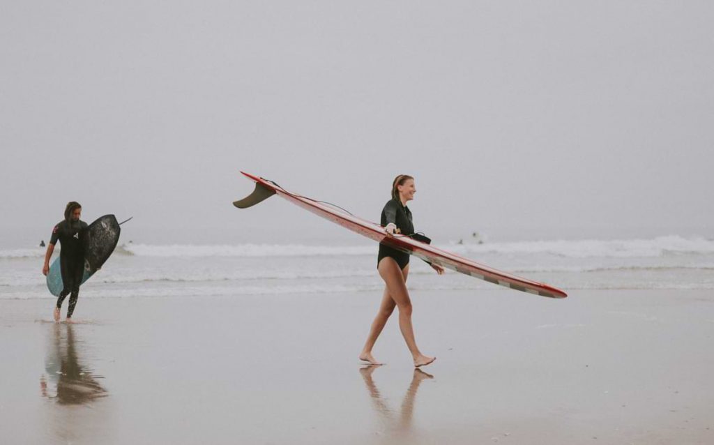 People carrying surfboards.